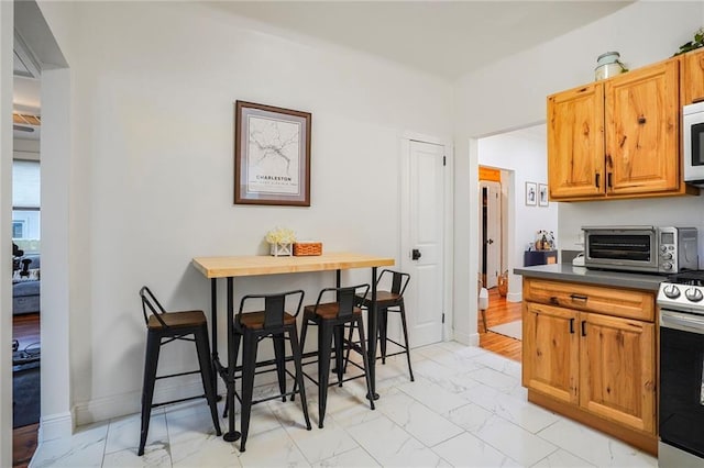 5839 Vicksburg St, New Orleans, LA 70124 - kitchen featuring dark countertops, stainless steel electric stove, marble finish floor, a toaster, and white microwave
