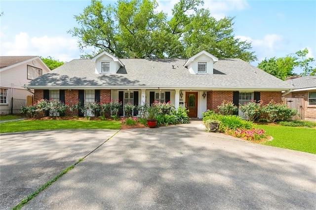 cape cod-style house featuring brick siding, a porch, and fence