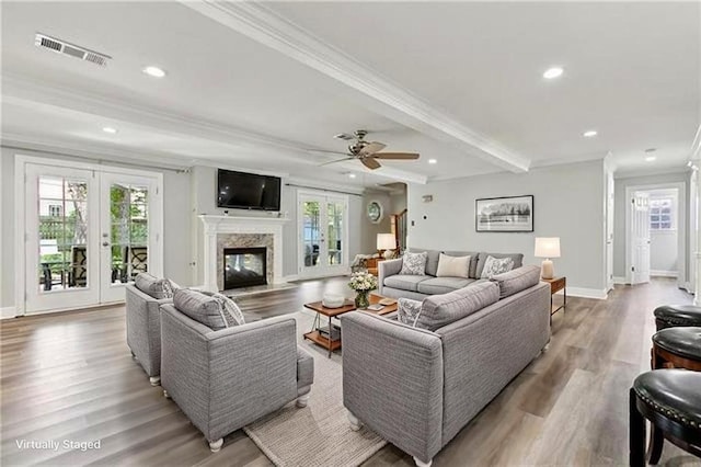 living room with light wood finished floors, plenty of natural light, french doors, and ornamental molding