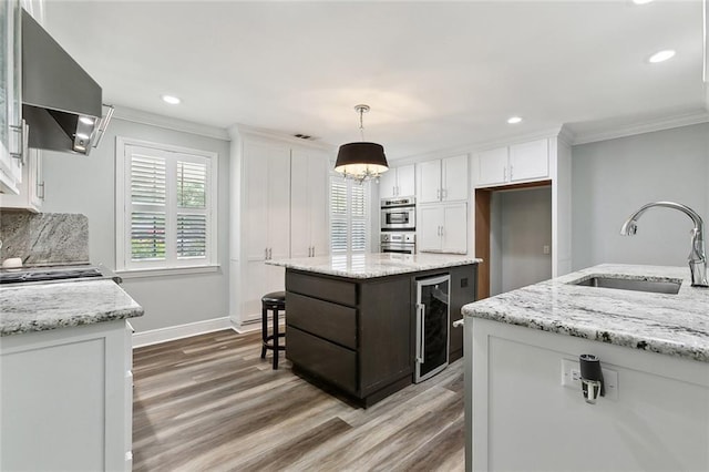 kitchen with crown molding, wood finished floors, a sink, beverage cooler, and exhaust hood