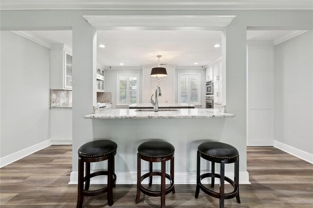 kitchen featuring a sink, white cabinets, a peninsula, dark wood-type flooring, and recessed lighting