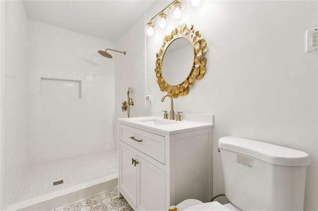 bathroom featuring tile patterned flooring, toilet, vanity, and tiled shower