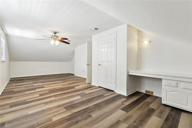 bonus room with baseboards, visible vents, lofted ceiling, wood finished floors, and ceiling fan
