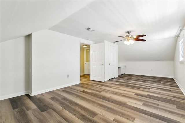 bonus room with a ceiling fan, wood finished floors, baseboards, lofted ceiling, and visible vents