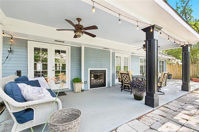 view of patio with visible vents, a ceiling fan, french doors, fence, and a fireplace