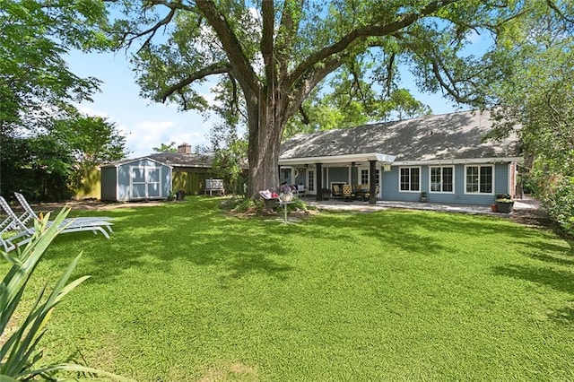 rear view of property with a patio area, an outdoor structure, a yard, and a shed