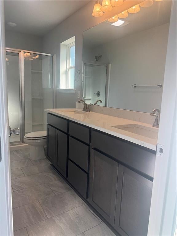 full bath featuring double vanity, a sink, a stall shower, and toilet