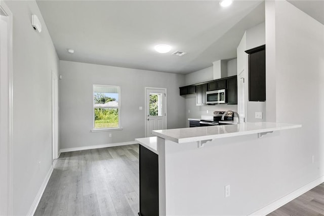 524 Helis Dr, Waggaman, LA 70094 - kitchen with stainless steel appliances, light countertops, light wood finished floors, and a breakfast bar area