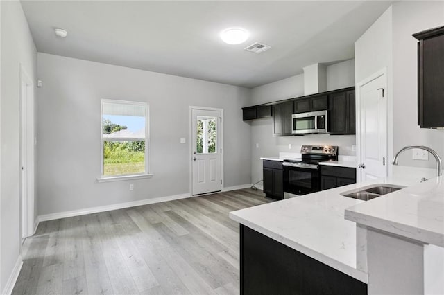 524 Helis Dr, Waggaman, LA 70094 - kitchen featuring stainless steel appliances, light wood-type flooring, light stone counters, and dark cabinetry