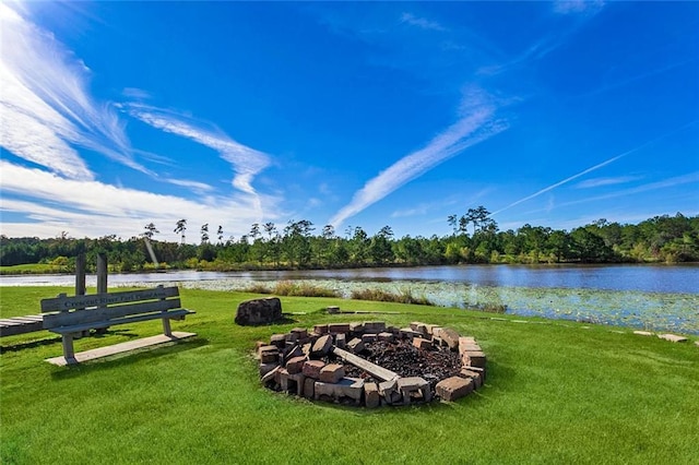 surrounding community with an outdoor fire pit, a water view, and a lawn
