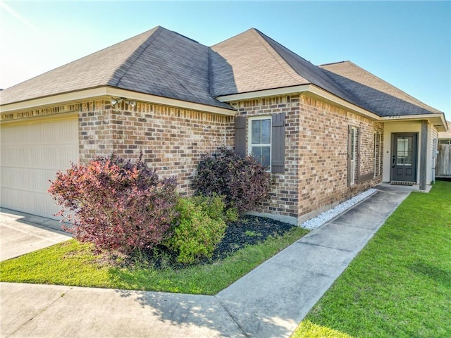 view of side of home with concrete driveway, a shingled roof, brick siding, and a garage