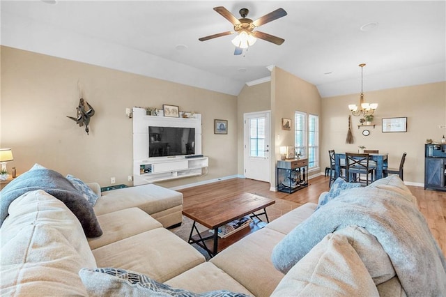 living area with vaulted ceiling, wood finished floors, ceiling fan with notable chandelier, and baseboards
