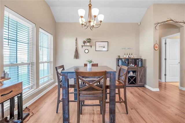 dining area with lofted ceiling, a chandelier, light wood finished floors, and baseboards