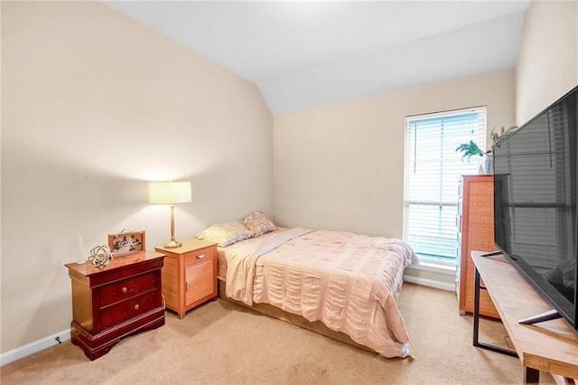 bedroom with light colored carpet, vaulted ceiling, multiple windows, and baseboards