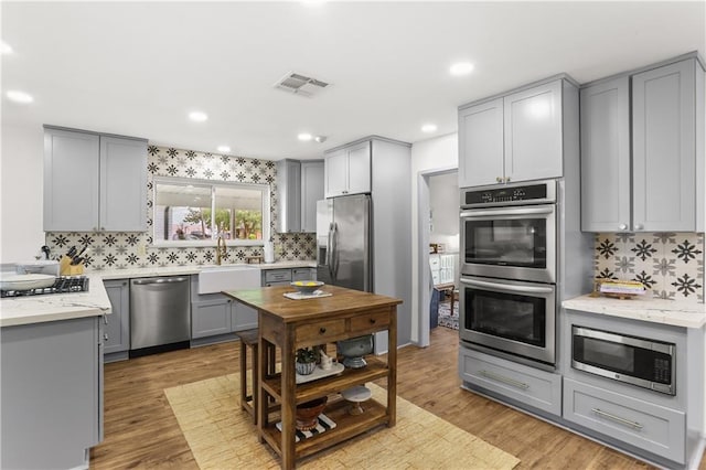 4716 Elmwood Pkwy, Metairie, LA 70003 - kitchen with stainless steel appliances, a sink, tasteful backsplash, visible vents, and gray cabinetry