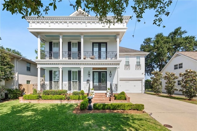 greek revival house with french doors, a balcony, concrete driveway, and covered porch