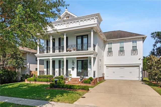 greek revival inspired property with a balcony, concrete driveway, an attached garage, covered porch, and a front yard