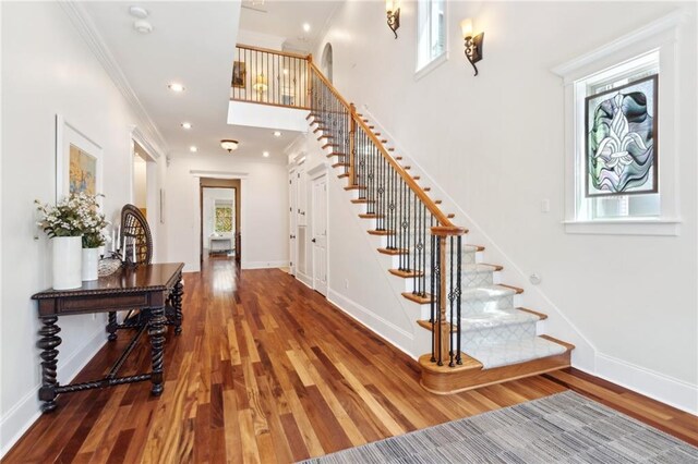 entryway with baseboards, wood finished floors, and stairway