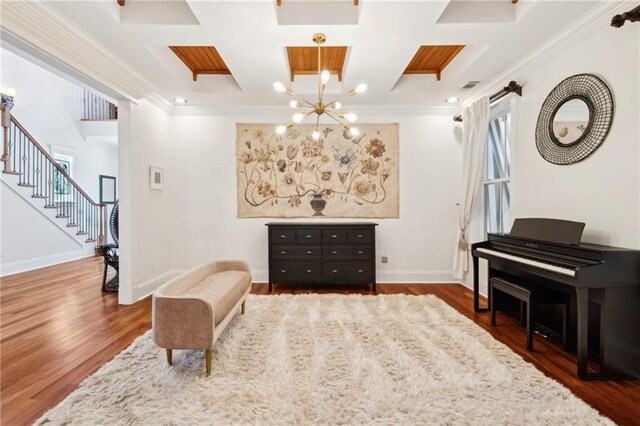 sitting room featuring baseboards, a chandelier, coffered ceiling, stairs, and crown molding
