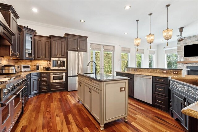 kitchen with backsplash, dark brown cabinets, a sink, glass insert cabinets, and appliances with stainless steel finishes