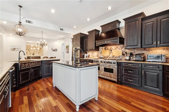 kitchen with a sink, double oven range, visible vents, custom exhaust hood, and a chandelier