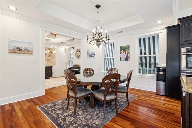 dining area featuring a raised ceiling, wood finished floors, crown molding, baseboards, and a chandelier