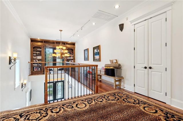 hall featuring baseboards, an upstairs landing, a chandelier, wood finished floors, and ornamental molding