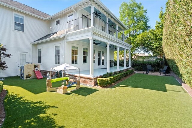 back of house featuring ceiling fan, a balcony, a yard, and a patio