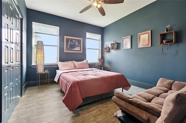 bedroom featuring baseboards, wood finished floors, a closet, and ceiling fan