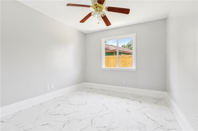 spare room featuring marble finish floor, baseboards, and ceiling fan
