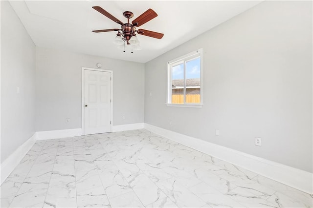 empty room with marble finish floor, baseboards, and a ceiling fan