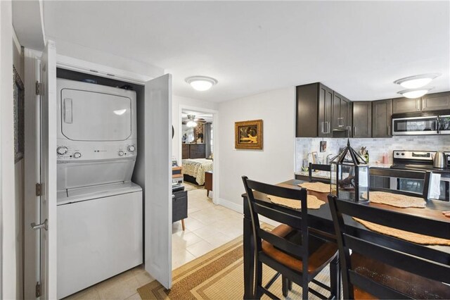 615 Filmore Ave, New Orleans, LA 70124 - kitchen with stainless steel appliances, estacked washer and dryer, light tile patterned flooring, backsplash, and a ceiling fan