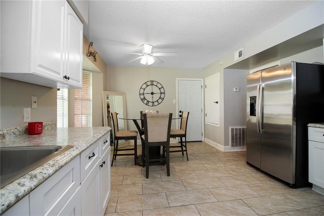 2172 Carmel Valley Dr, La Place, LA 70068 - kitchen with stainless steel fridge, a ceiling fan, visible vents, and white cabinets