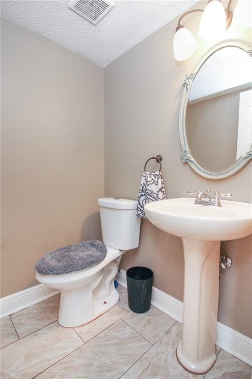 2172 Carmel Valley Dr, La Place, LA 70068 - bathroom featuring toilet, a textured ceiling, visible vents, and baseboards