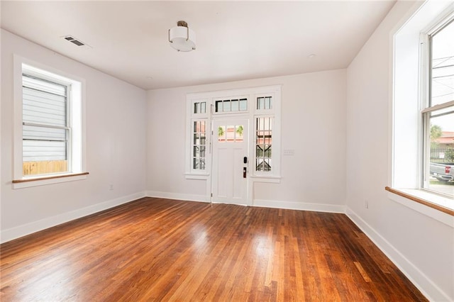 empty room featuring baseboards, wood finished floors, and visible vents