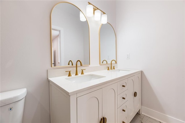bathroom with marble finish floor, baseboards, a sink, and double vanity