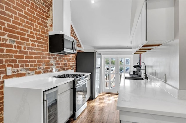 818 Bourbon St Unit 3A, New Orleans, LA 70116 - kitchen with appliances with stainless steel finishes, wine cooler, light countertops, a sink, and light wood-style floors
