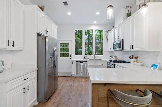 71463 Haynes St, Abita Springs, LA 70420 - kitchen featuring visible vents, a sink, decorative backsplash, a peninsula, and appliances with stainless steel finishes