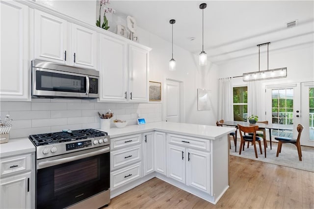 71463 Haynes St, Abita Springs, LA 70420 - kitchen with light countertops, visible vents, light wood-style floors, tasteful backsplash, and appliances with stainless steel finishes