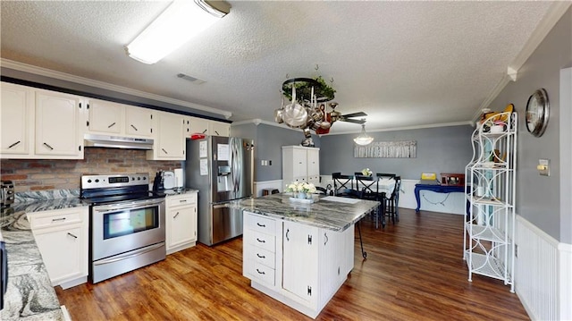 31763 Shelton Dr, Springfield, LA 70462 - kitchen featuring crown molding, a textured ceiling, stainless steel appliances, under cabinet range hood, and visible vents