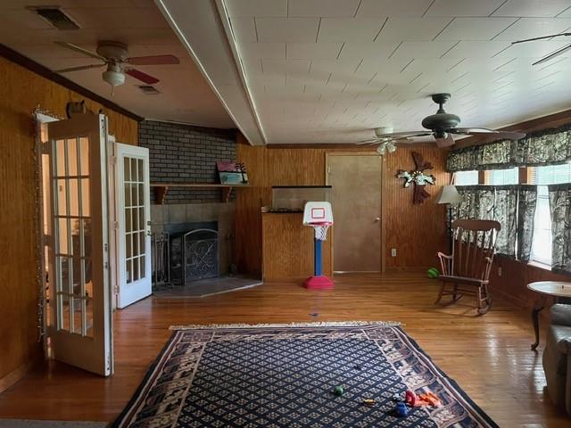 46038 Wooding Ln, Franklinton, LA 70438 - living room featuring a ceiling fan, wooden walls, wood finished floors, and a fireplace