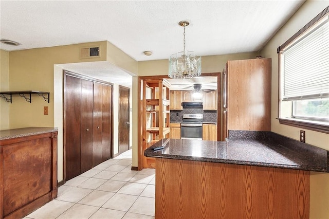 716 N Woodlawn Ave, Metairie, LA 70001 - kitchen with stainless steel range with electric cooktop, under cabinet range hood, a peninsula, backsplash, and light tile patterned floors