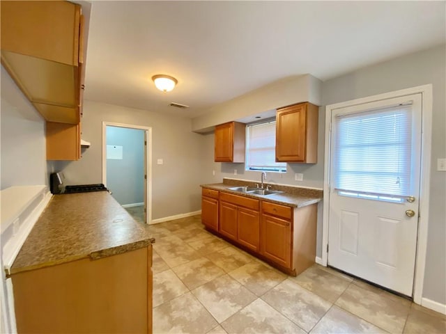 kitchen with brown cabinets, light tile patterned flooring, a sink, range, and baseboards