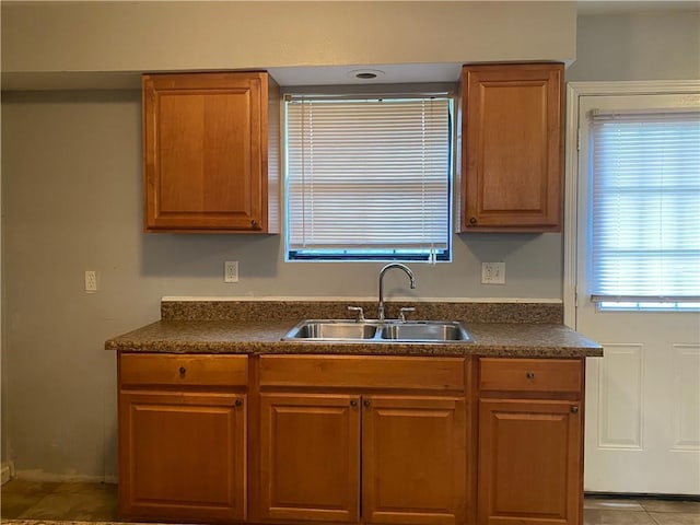 kitchen featuring brown cabinetry, a sink, and dark countertops