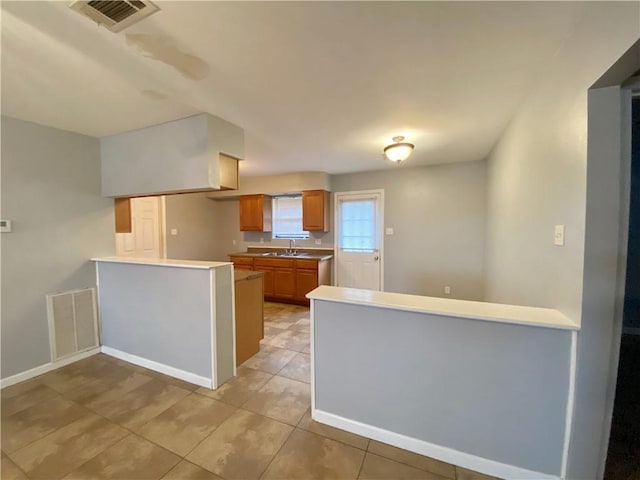 kitchen featuring visible vents, light countertops, a peninsula, and light tile patterned flooring