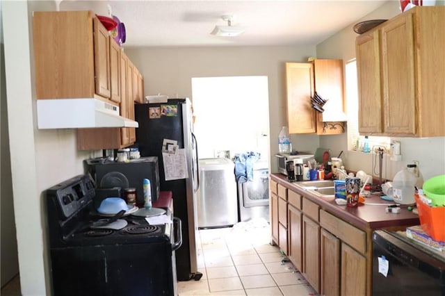 kitchen with dark countertops, extractor fan, light tile patterned floors, washing machine and dryer, and black appliances