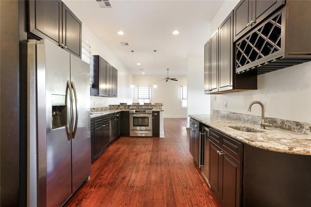 842 Toledano St, New Orleans, LA 70115 - kitchen with a ceiling fan, a sink, stainless steel appliances, a peninsula, and dark wood-style floors