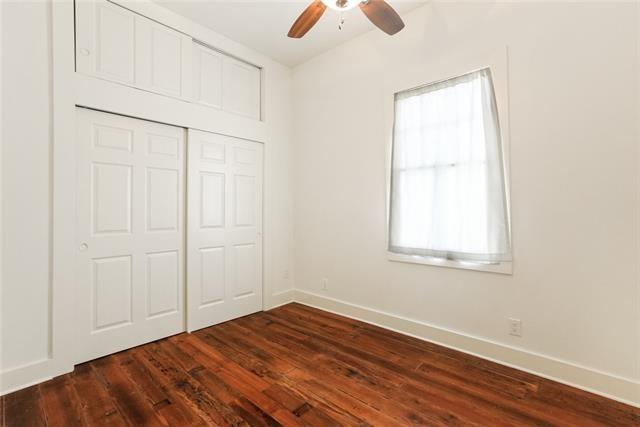 842 Toledano St, New Orleans, LA 70115 - unfurnished bedroom featuring a ceiling fan, baseboards, a closet, and dark wood-style flooring