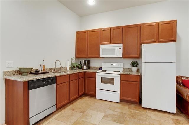 842 Toledano St, New Orleans, LA 70115 - kitchen featuring brown cabinets, light stone counters, a sink, and white appliances