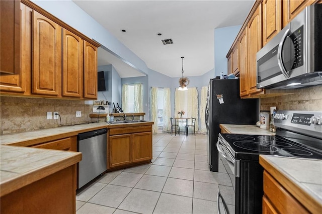 52475 Wilson Rd, Folsom, LA 70437 - kitchen featuring appliances with stainless steel finishes, backsplash, brown cabinets, a sink, and vaulted ceiling